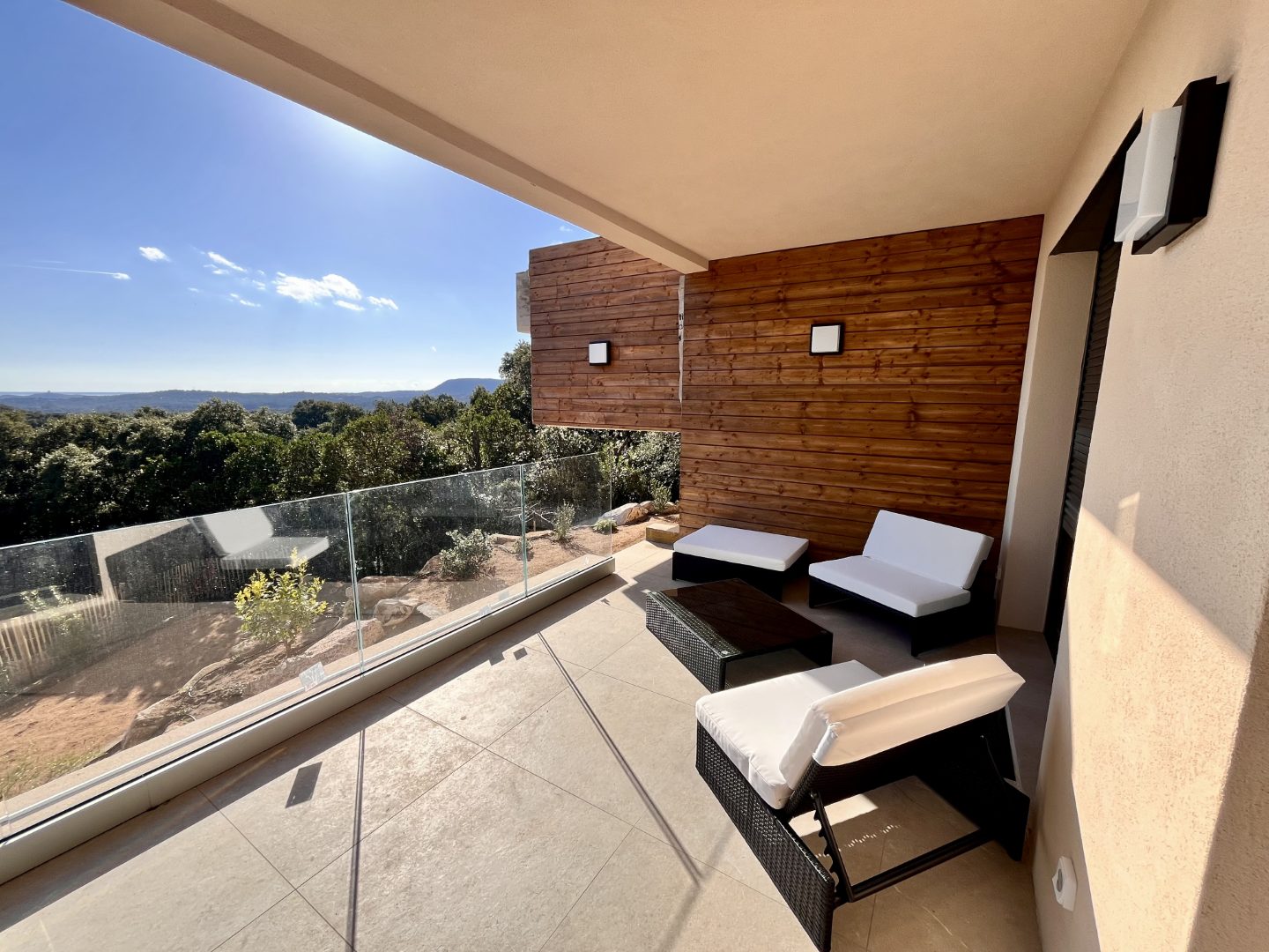 La terrasse du bas, son bardage bois et ses fauteuils face au maquis et aux montagnes.